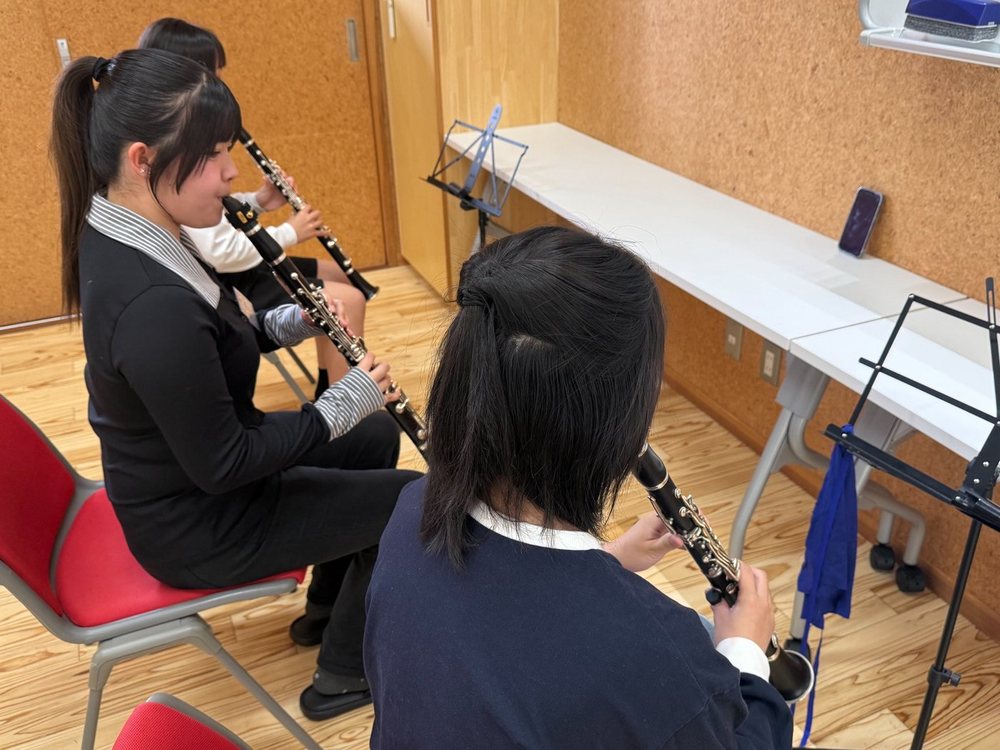 大学生と中学生が並んでクラリネットを吹いている様子