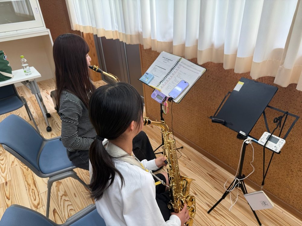 レッスンで、大学生が中学生にサクソフォンの演奏を教えている様子